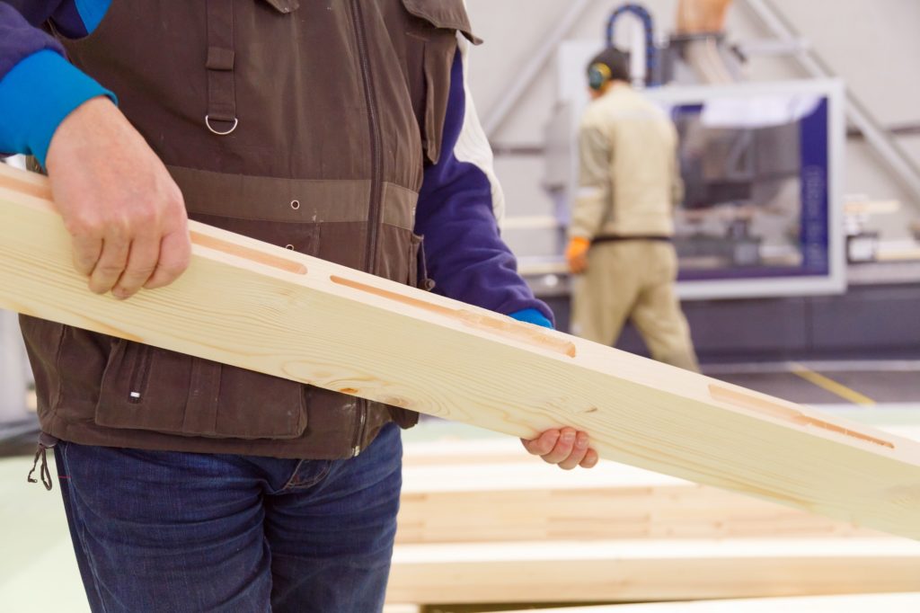 Carpenter with a planed board in his hands, a close-up of a worker at the enterprise.