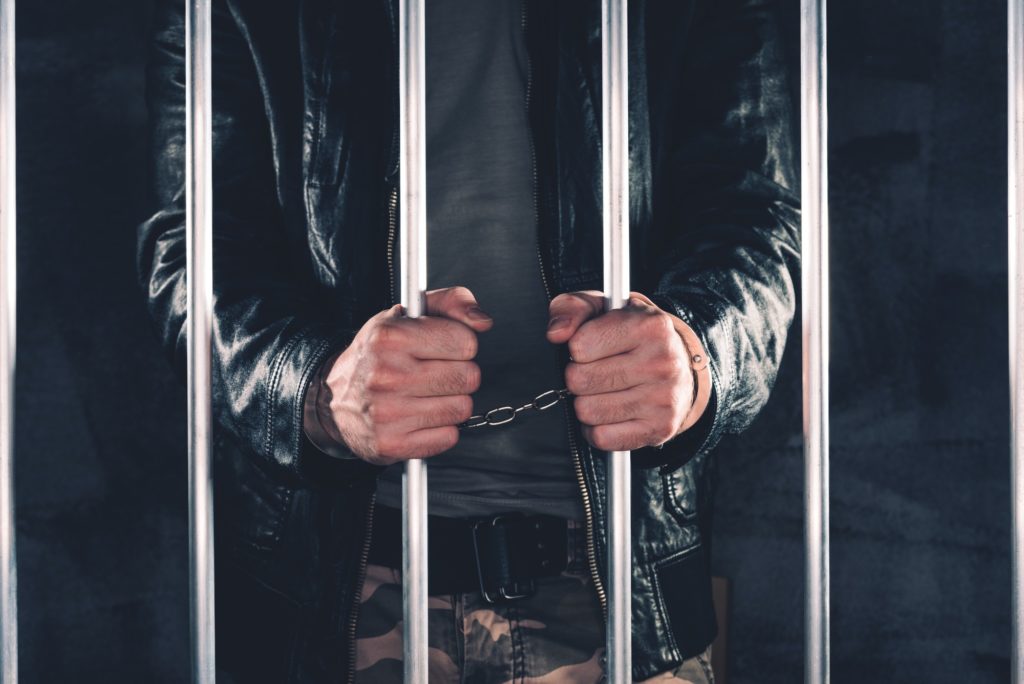 Handcuffed man behind prison bars